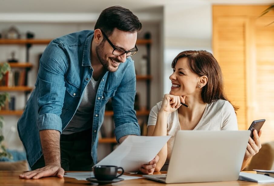 Smiling couple looking at documents at home office, portrait.